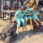 bronze Statues of a boy and girl playing with a butterfly on a tree stump
