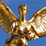 Close-up of golden bronze angel statue facial and wreath details