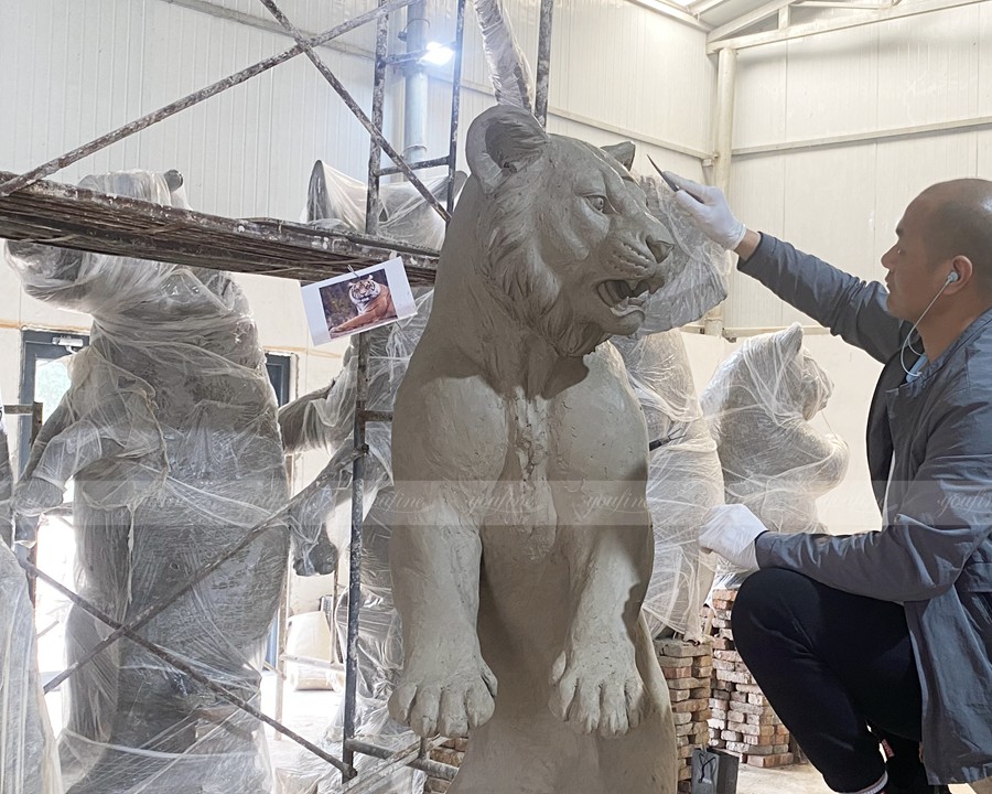 Modifying the clay model of a tiger sculpture