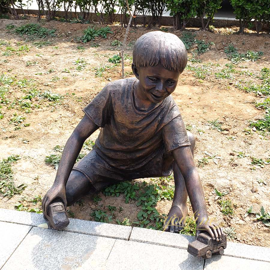 Sculpture of a child playing with a car