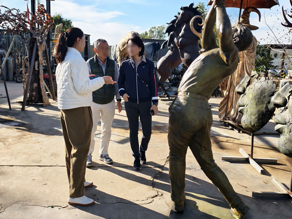 Art consultant inspecting bronze patina finishes at the YouFine workshop