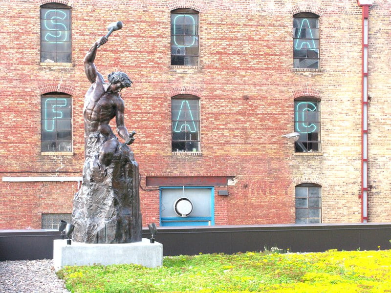 Self Made Man bronze statue -- a man pulling himself up from the ground, symbolizing ambition and perseverance