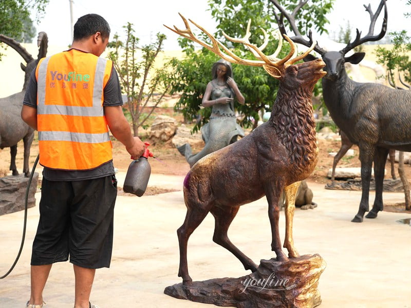 Artisan applying patina finish to bronze elk antlers