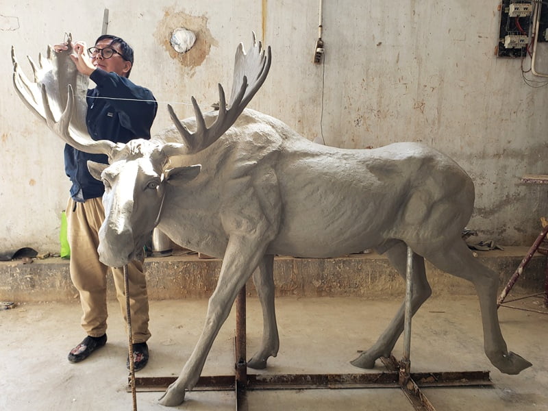 Master sculptor creating 1:1 clay model of moose with precise anatomical details