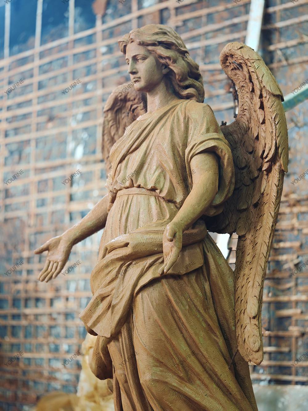 Clay model detail showing the angel’s face, hands, drapery, and feathered wing.