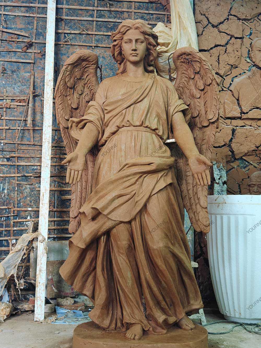 Front view of a full angel clay model with open hands and wings.