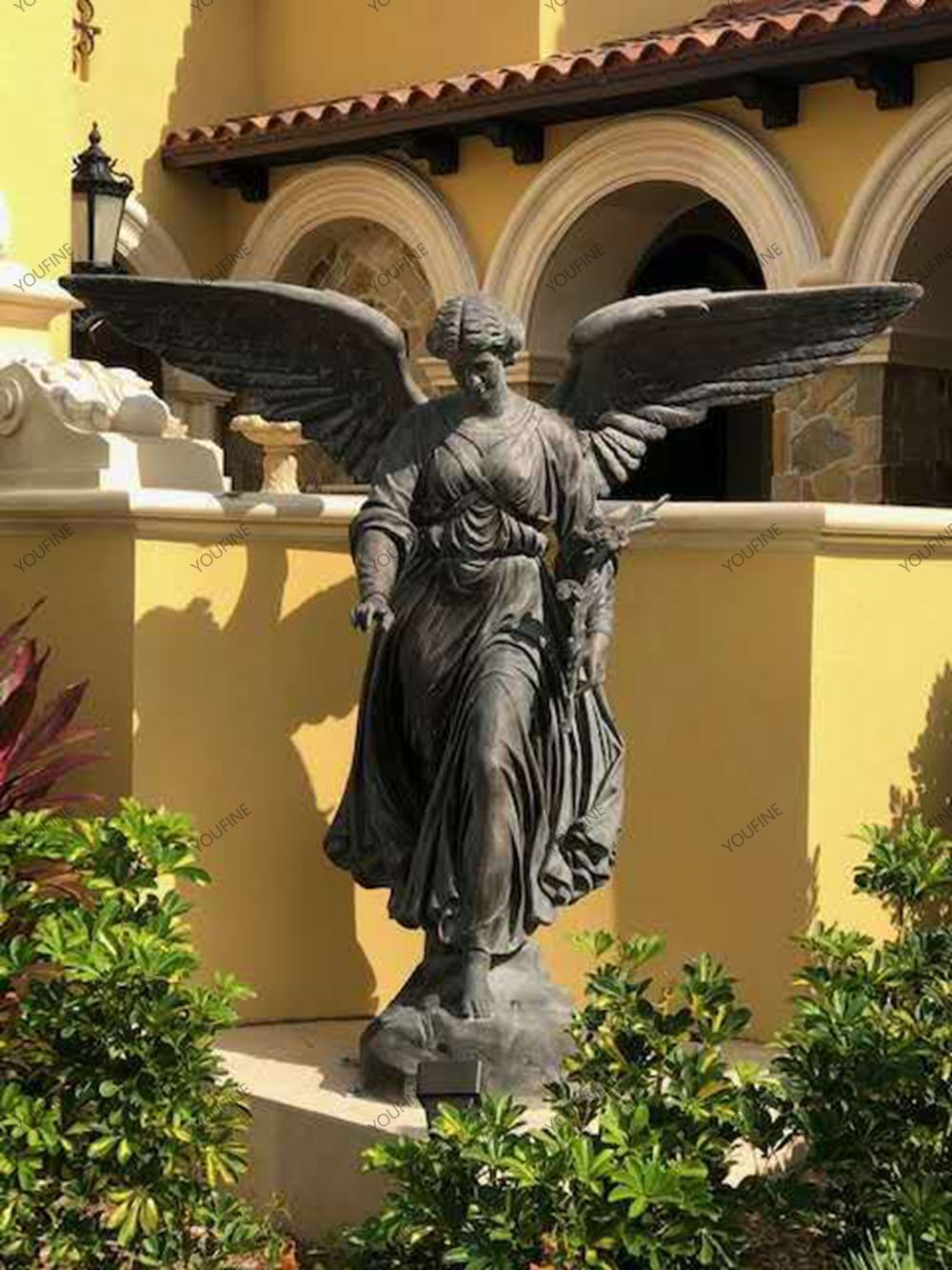 Bronze angel sculpture installed in a landscaped courtyard