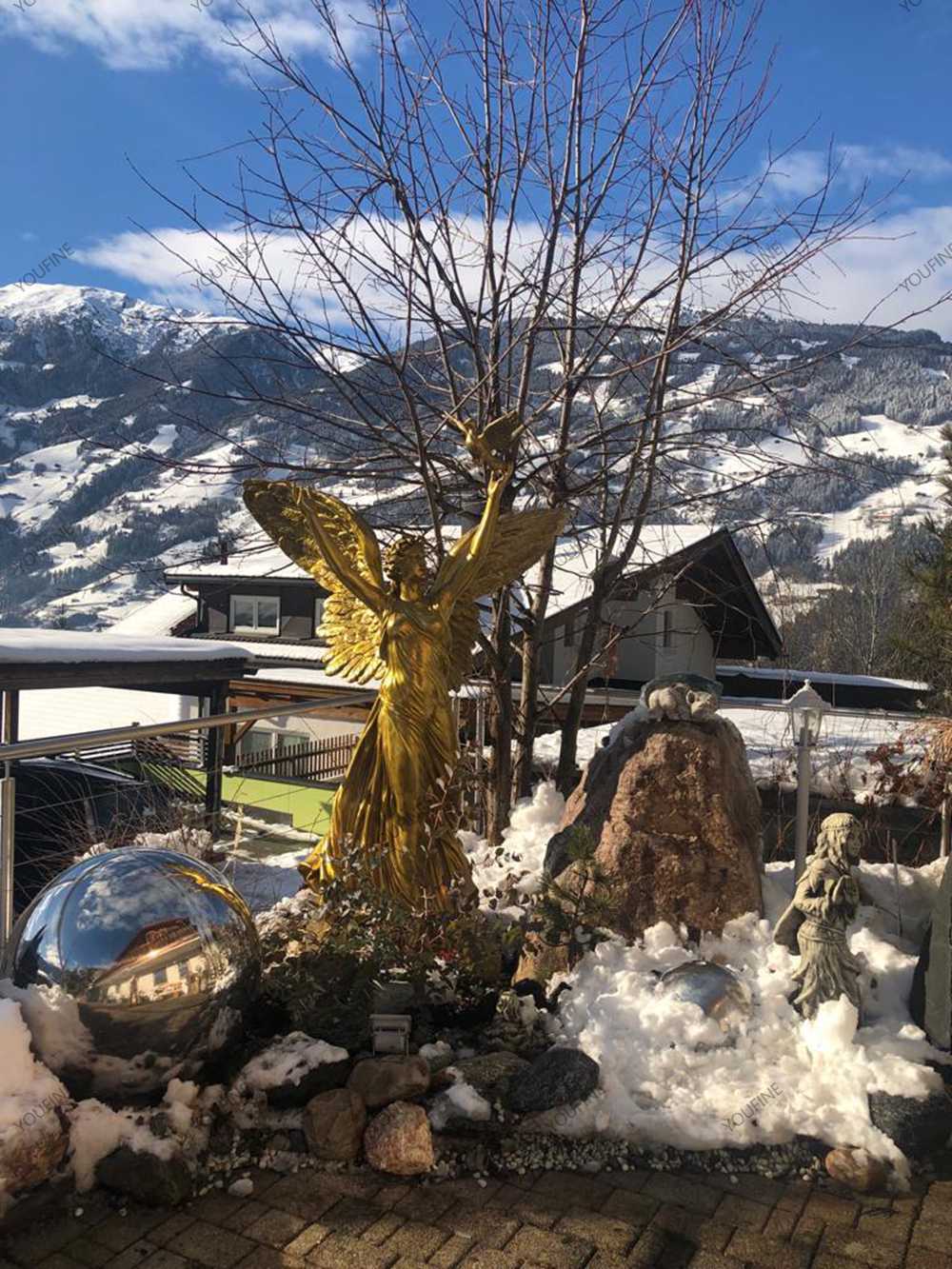 Golden bronze angel sculpture installed in a snowy garden