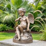 Seated bronze cherub statue displayed in a garden
